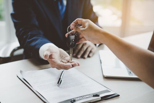 An auto notary handing keys and signed documents to a buyer