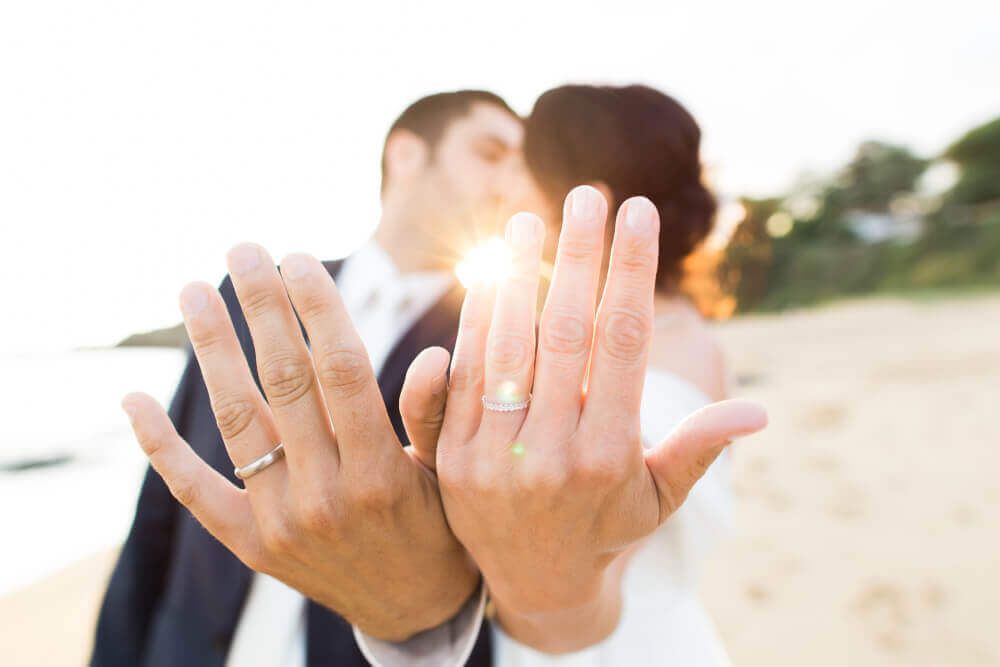 A newly wedded couple showing rings on a Florida beach