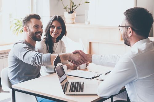 A couple shaking hands with their signing agent